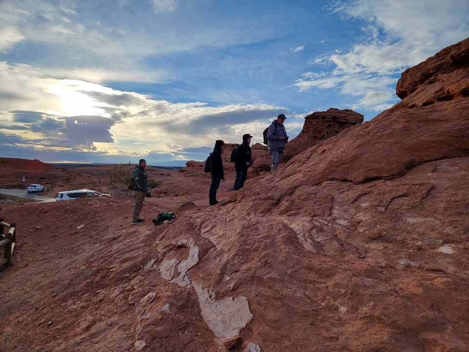 Veterans climbing red sandstone with their RC crawlers under a wide sky