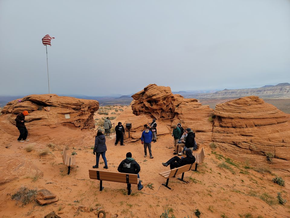 Members crawling RC trucks among red rock formations beside an American flag