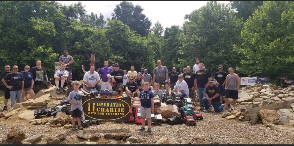 Big O11C group photo behind the Operation 11 Charlie banner with everyone's rigs