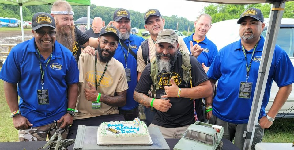 O11C members gathered around a celebration cake at an event